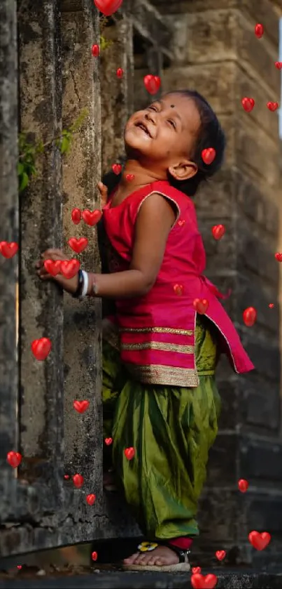 Adorable child smiling by a rustic wall in vibrant clothing.