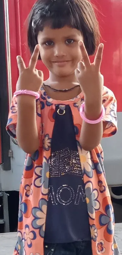 Joyful child in a floral outfit with red background.