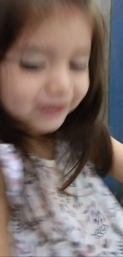 Blurry image of a joyful child in motion against a blue background.