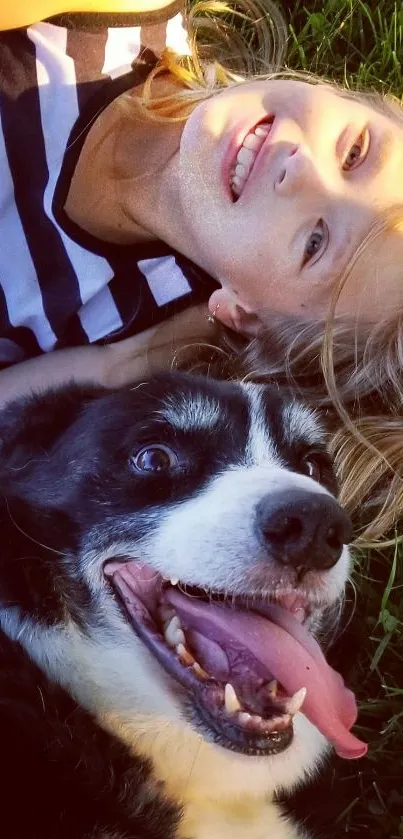 Smiling child laying with happy dog on grass.