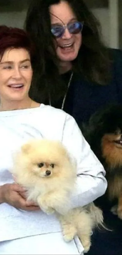 Joyful couple holding adorable Pomeranians, smiling warmly.