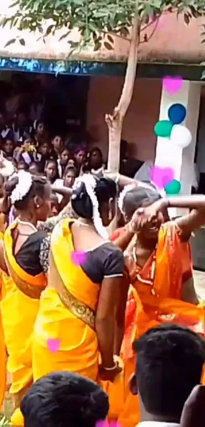 Dancers in orange sarees performing at a festive event.