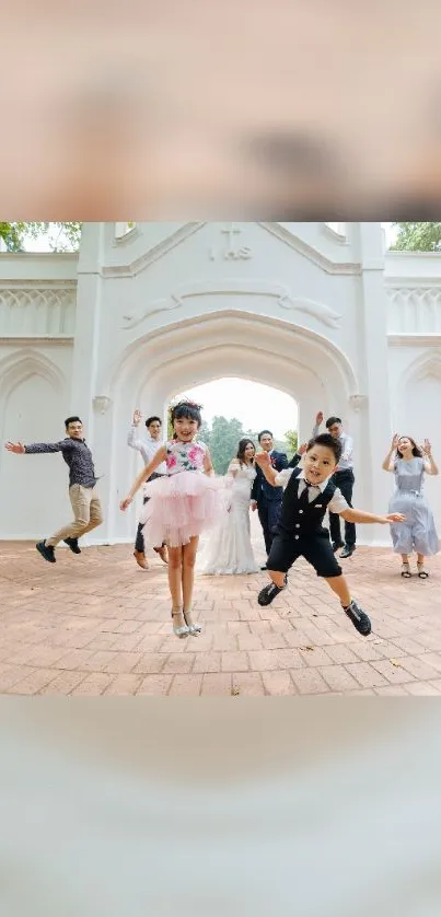 Family and kids jumping joyfully by a white arch.