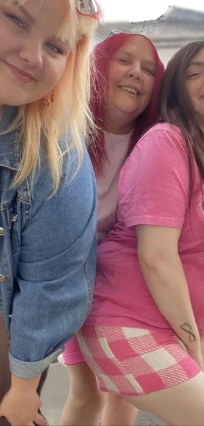 Three friends pose happily in pink on a sunny day.