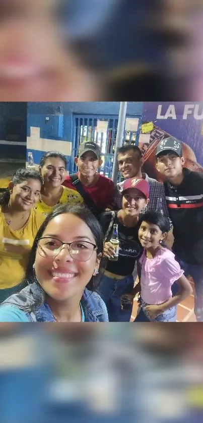 A cheerful group of people smiling for a photo outdoors at night.