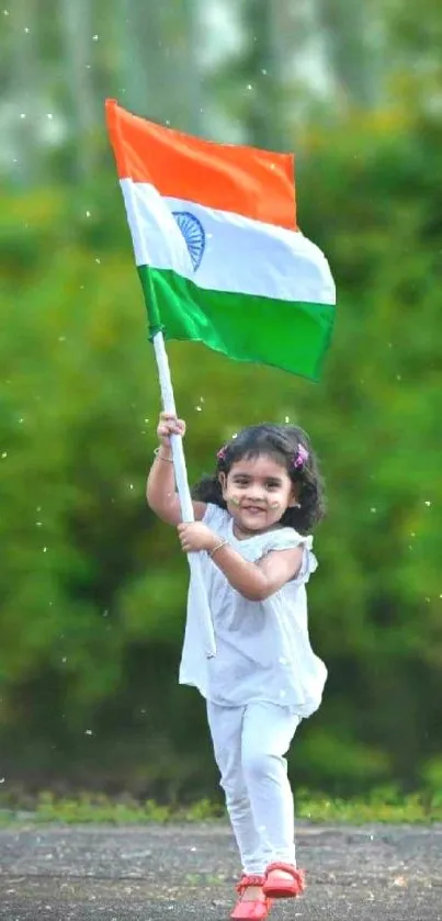 Girl joyfully waves Indian flag with lush greenery backdrop.