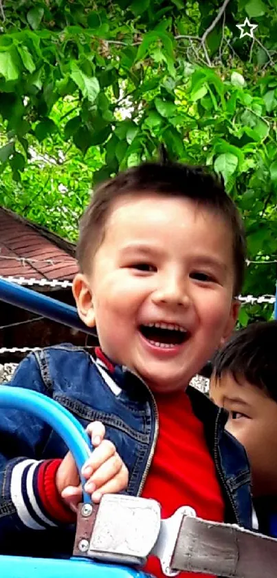 Two children smiling on a theme park ride with green leaves in background.