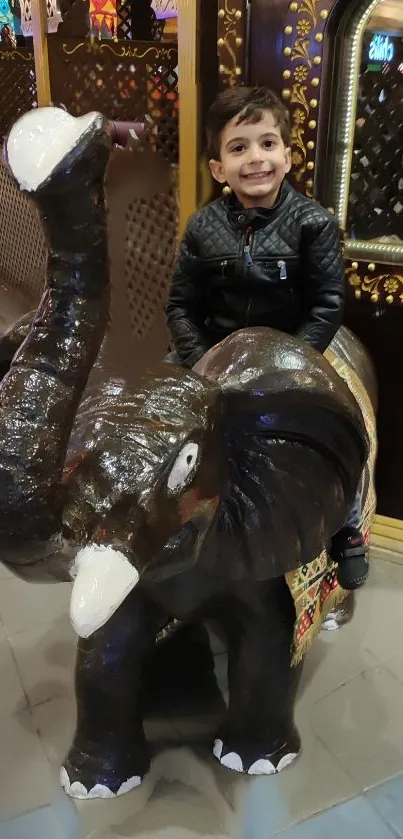 Boy joyfully rides a decorative elephant statue indoors.