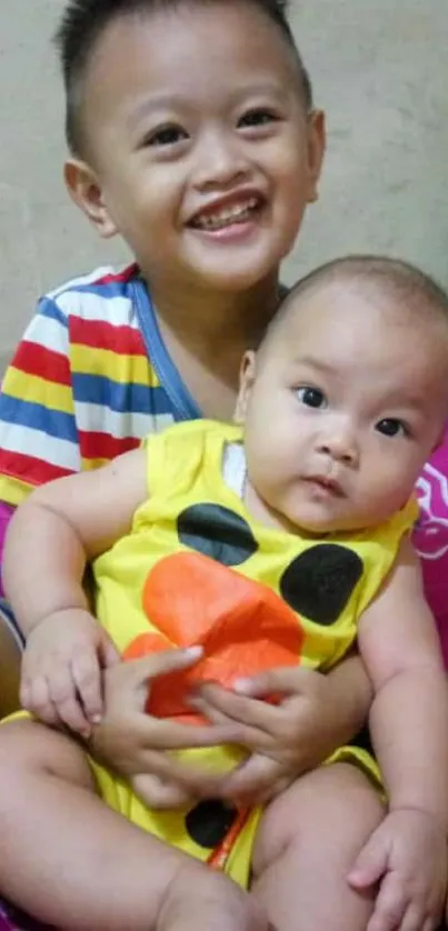 Two smiling kids with colorful outfits on a bright pink bedspread.