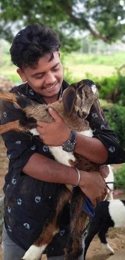 Person happily holding a baby goat in a lush green countryside setting.