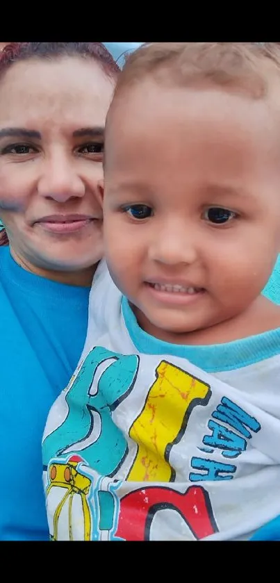 Woman with toddler smiling against a blue background.