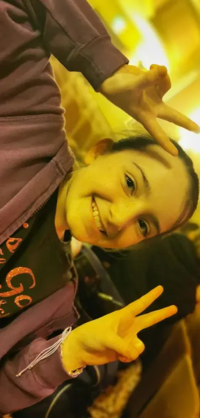 Smiling girl in purple jacket giving peace signs in a theater setting.