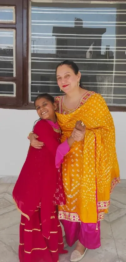 Mother and daughter hugging in colorful traditional attire.