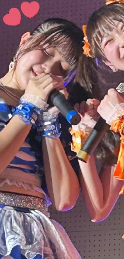 Two smiling singers on stage with microphones.