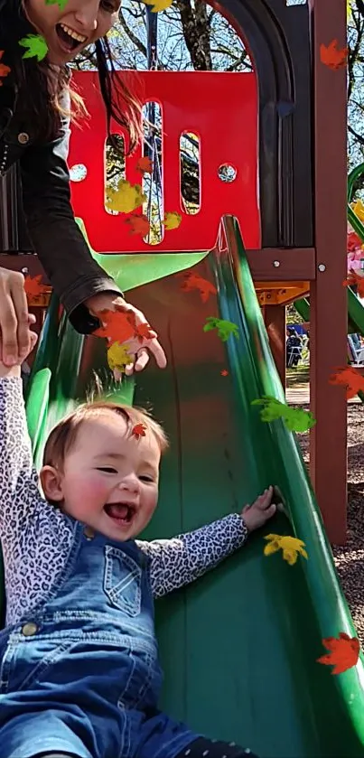 Child laughing on a playground slide with autumn leaves.