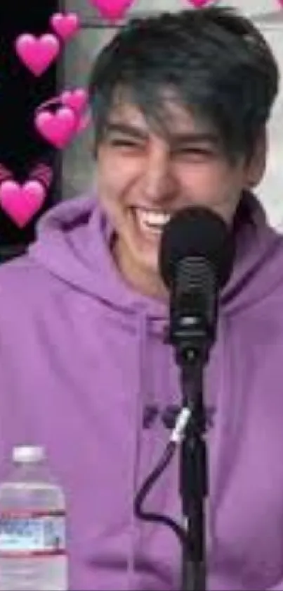 Smiling person with purple hoodie surrounded by pink hearts.