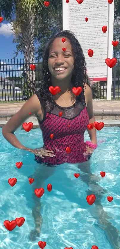 Girl smiling in pool with red hearts.