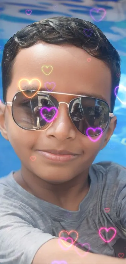 Smiling boy in sunglasses by the pool with heart effects.