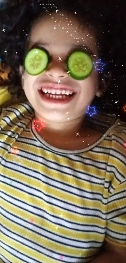 A joyful child relaxing with cucumber slices on eyes on a colorful blanket.