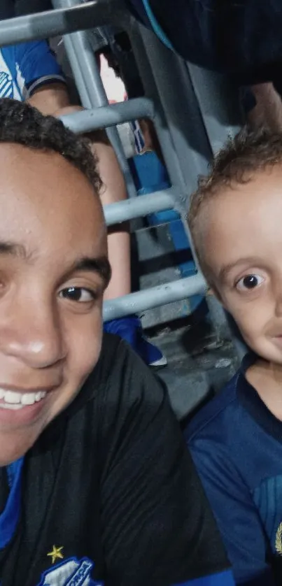 Two smiling kids in blue football jerseys enjoying a game.