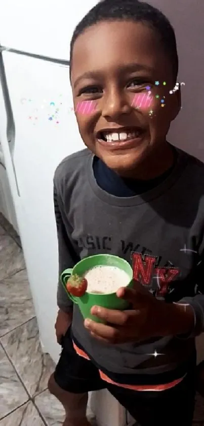 Smiling child with animated cheeks holding a green cup in a kitchen.