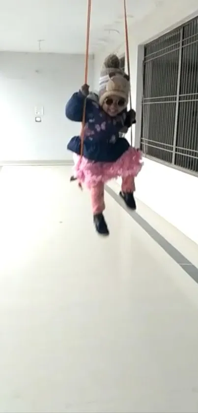 Child in winter outfit swinging indoors joyfully.