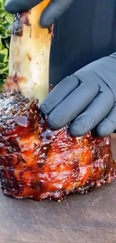 Gloved hand holding a juicy grilled beef bone.