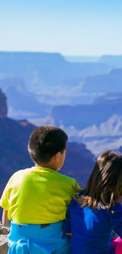 Children sitting overlooking a stunning canyon view with blue skies.