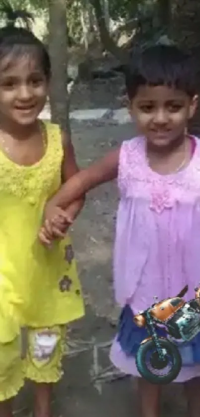 Two children playing outdoors in colorful dresses.