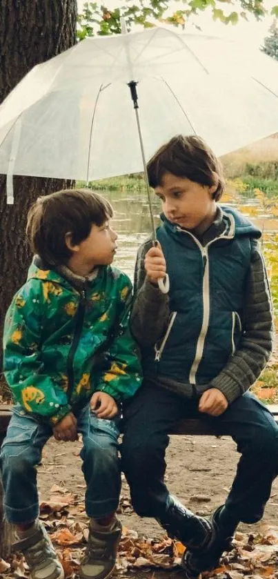 Two kids under a clear umbrella in a park with autumn leaves.