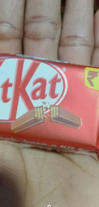 Close-up of a KitKat candy bar in red packaging on a hand.