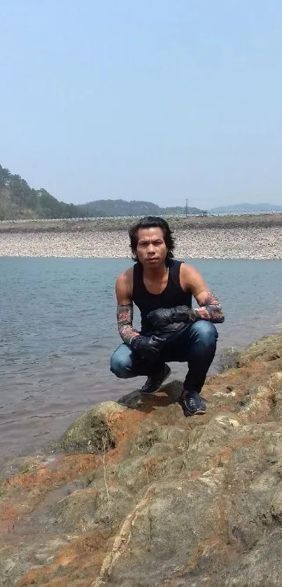 Person by the lake with mountains in the distance on a sunny day.