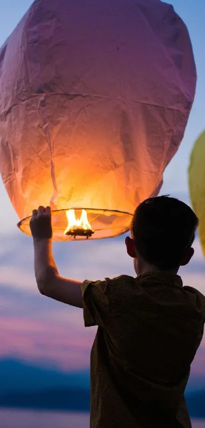 A boy releases a glowing lantern at twilight.
