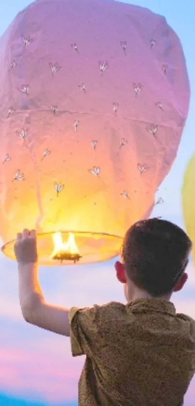 Child holding glowing lantern at sunset sky.