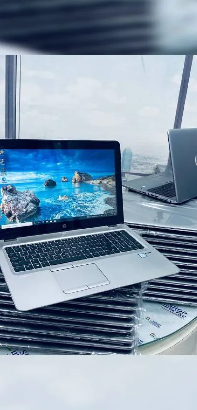 Laptops stacked with ocean view screensaver in a modern setting.