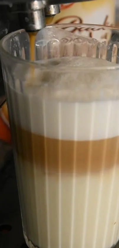 Layered latte in a clear glass with coffee machine.