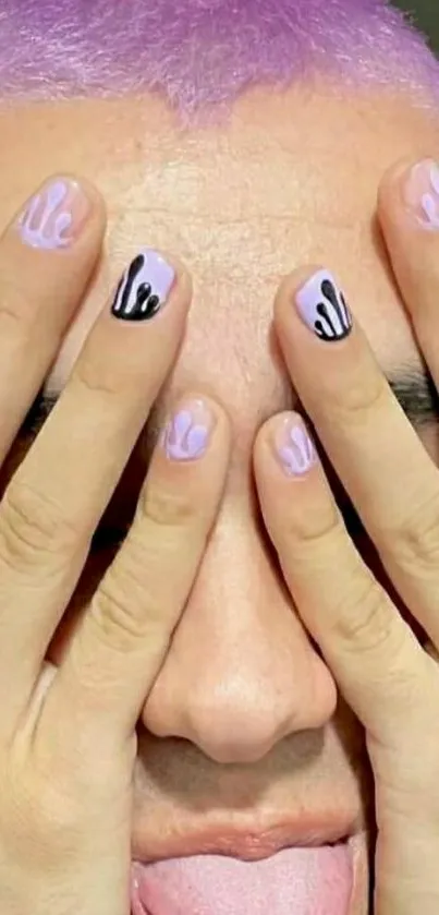 Person with lavender hair covers face with funky nail art.