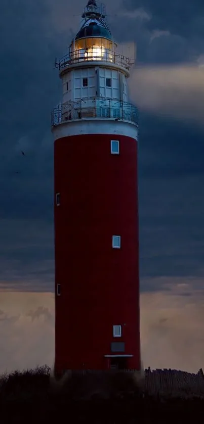 Lighthouse glowing against a dark blue dusk sky.