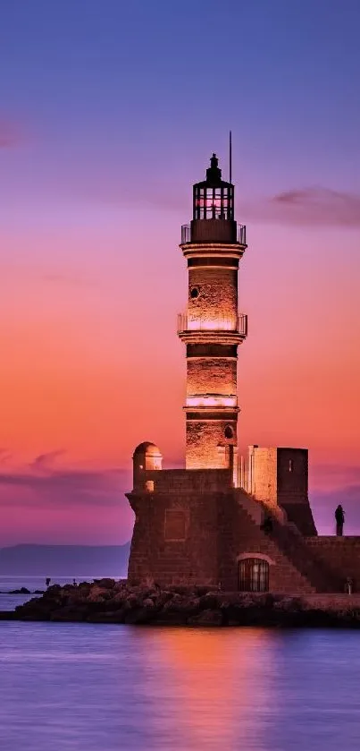 Lighthouse silhouetted against a vibrant orange sunset over the ocean.