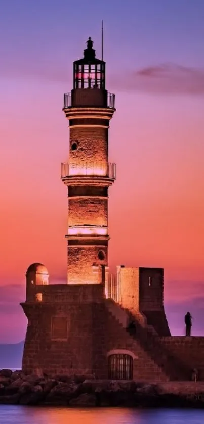 Lighthouse silhouette with vibrant sunset sky over calm ocean.