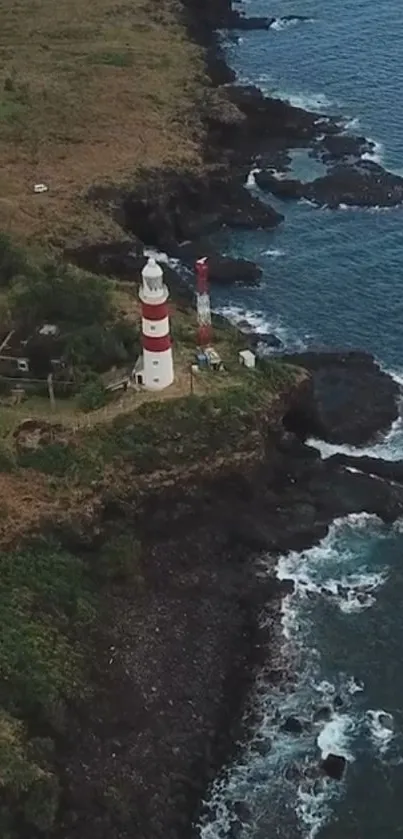 Aerial view of lighthouse on ocean cliff with crashing waves.