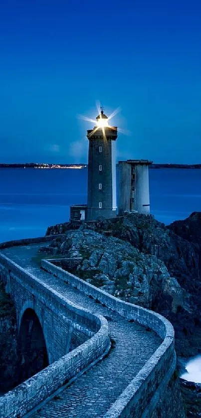 Serene lighthouse by the sea under a blue night sky, illuminating the rocky coastline.