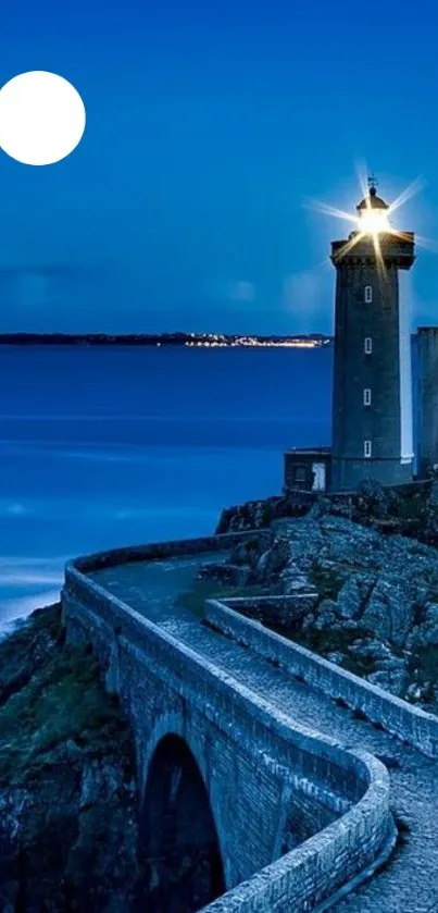 Lighthouse with moon in deep blue night sky and calm ocean view.