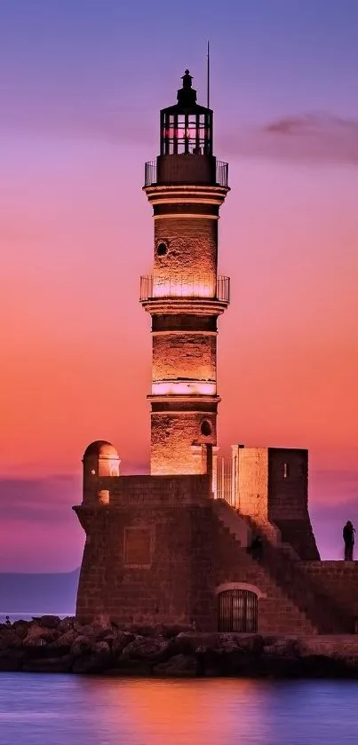 Lighthouse at sunset with purple and orange sky reflecting on the calm ocean.