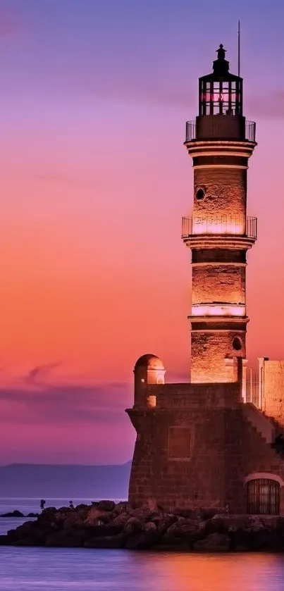 Lighthouse with vibrant sunset sky reflecting on ocean water.