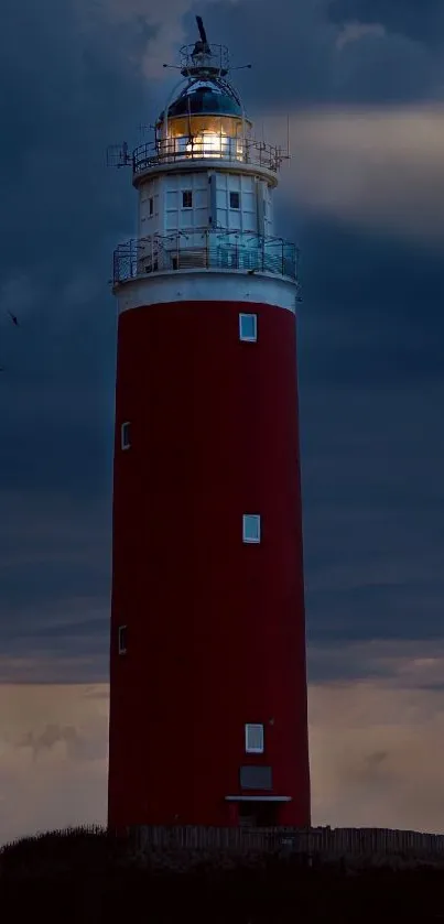 Red lighthouse against a dramatic dark blue sky at dusk.