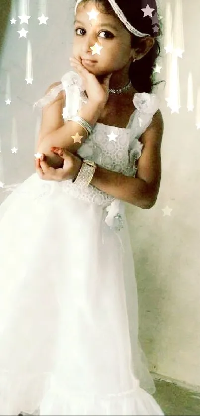 Little girl in elegant white dress posing against a plain wall.