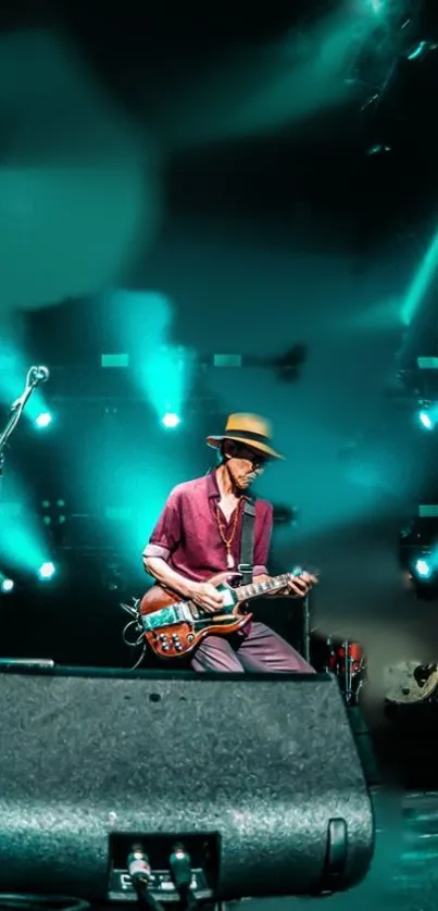 Guitarist performing live on stage with vibrant teal lights in background.