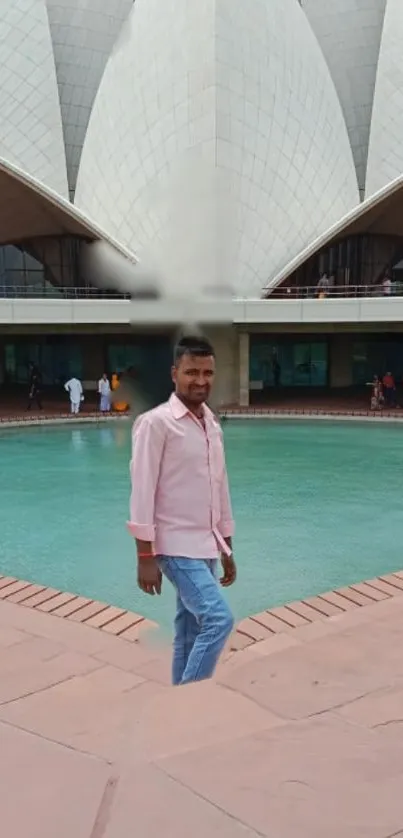 Man standing by Lotus Temple with serene water view.