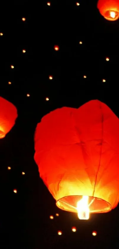 Glowing red lanterns illuminating a starry night sky.